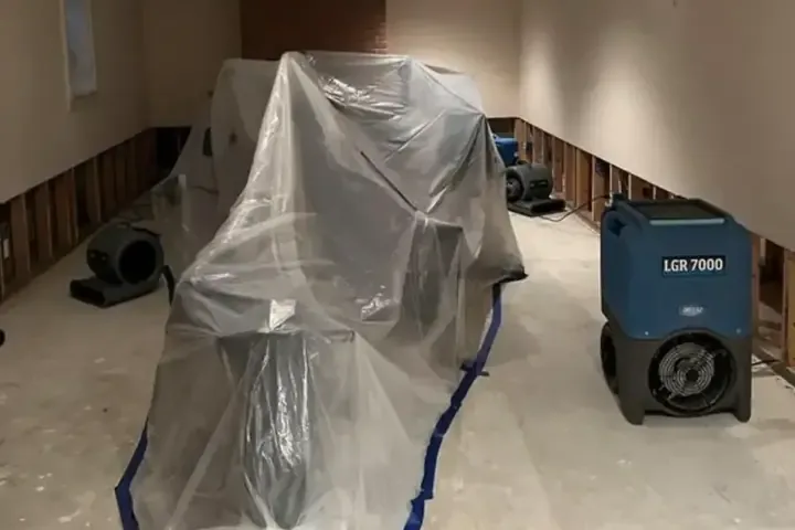 Plastic containment and an LGR dehumidifier drying a room with the lower walls cut open