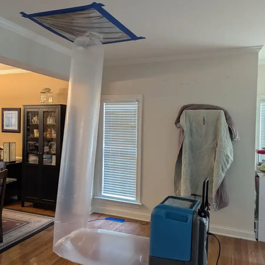 A containment tube and a dehumidifier drying a soaked living room ceiling
