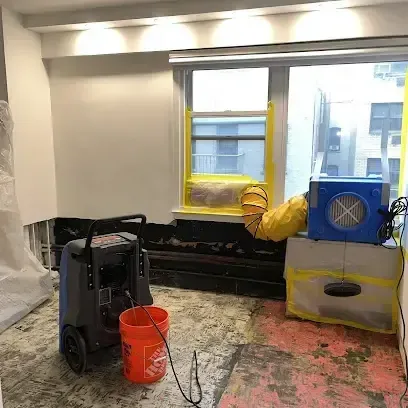 A dehumidifier and an air mover set up to dry a room after the wet flooring was taken out