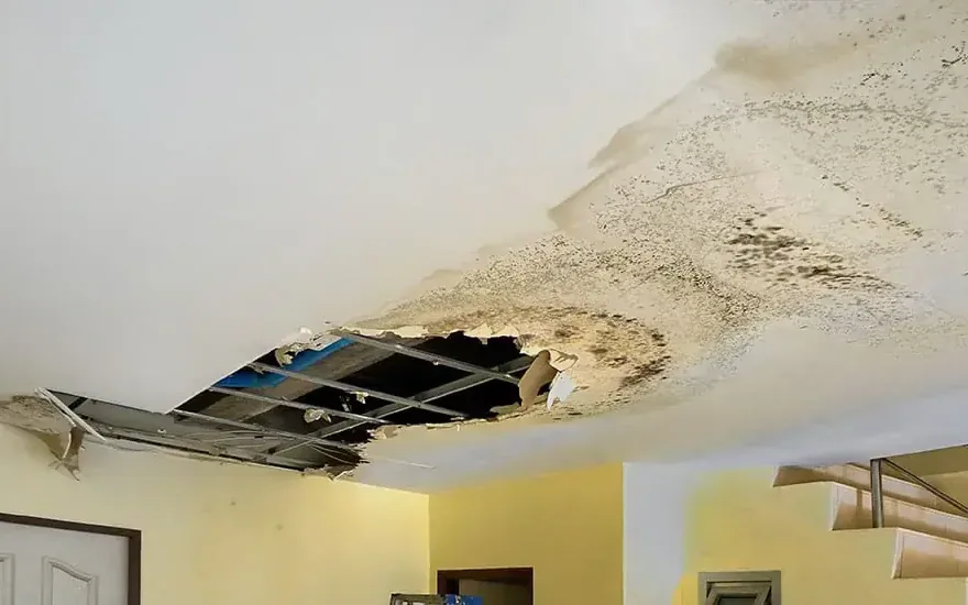 A stained ceiling cut open after a leak from above