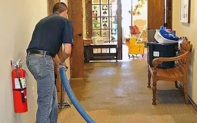 An extraction hose run across a soaked floor while standing water is pulled out of a home